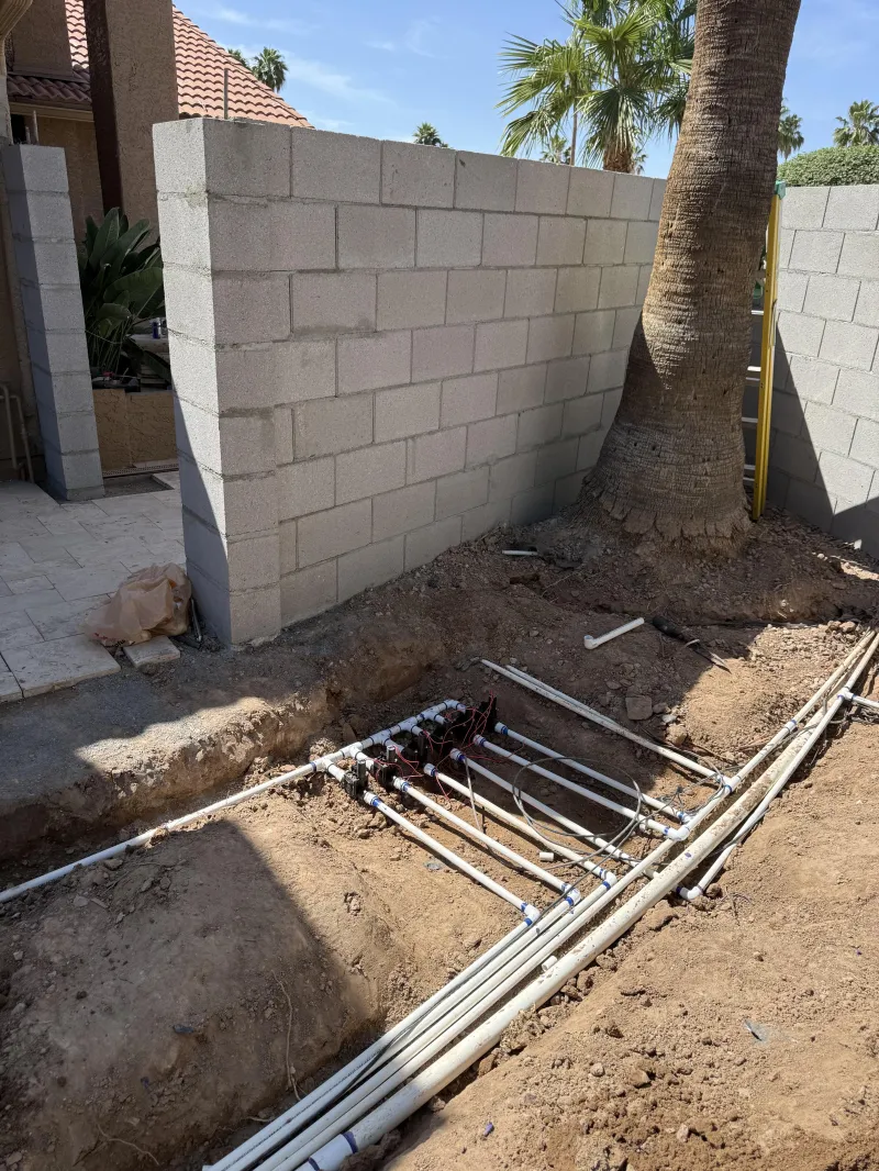 New irrigation lines and valve manifold being installed along a block wall, irrigation systems Phoenix AZ