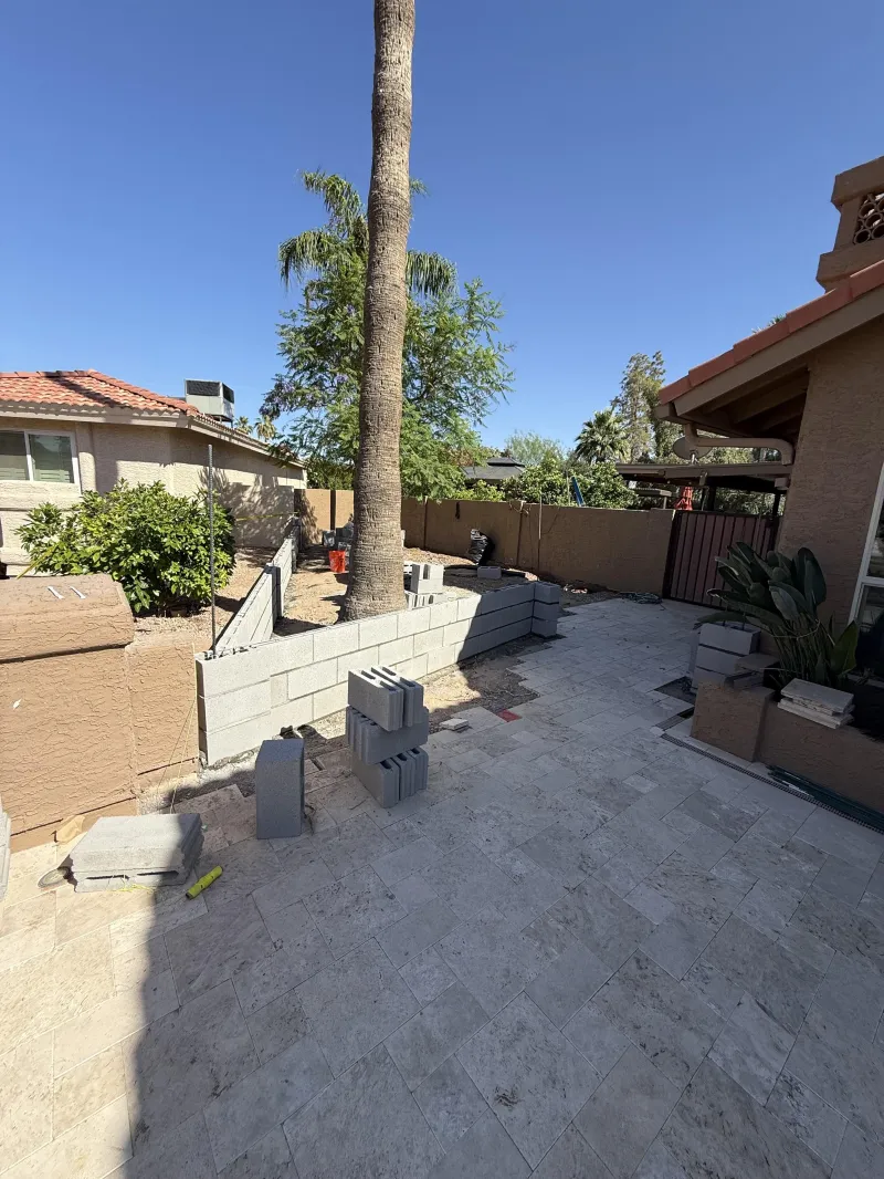 Block wall under construction beside a new travertine paver patio, block wall installation Phoenix AZ