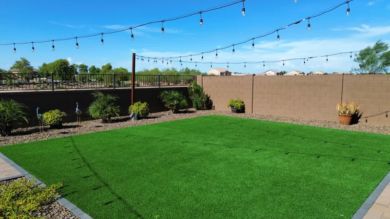 Backyard artificial turf lawn with string lights, desert plants, and block wall, turf installation Phoenix AZ