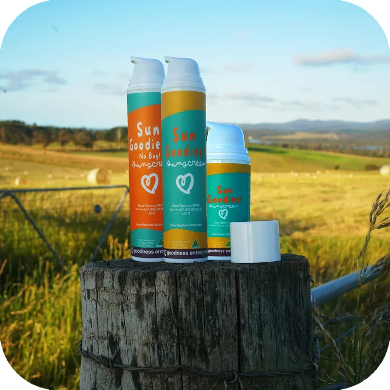 The Sun Goodies sunscreen range lined up on a timber fence post with hay bales and hills behind