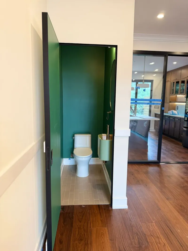Powder room painted in deep green with new hardwood floor