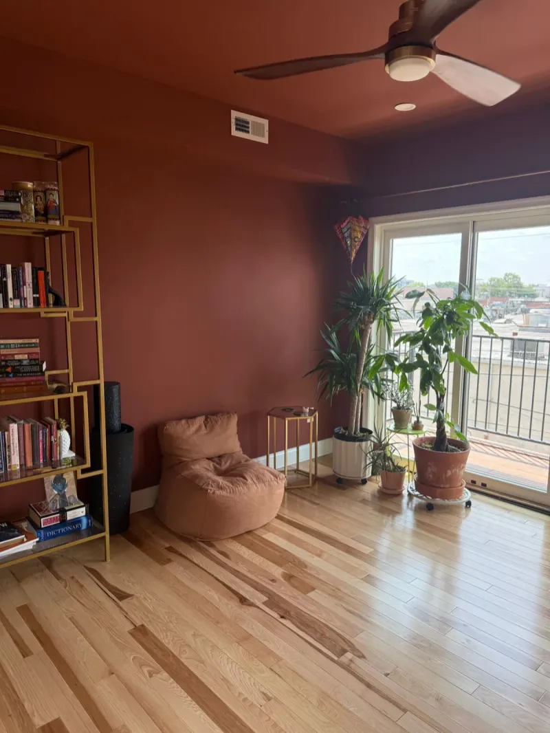 Den with a terracotta painted accent wall and natural hardwood floor