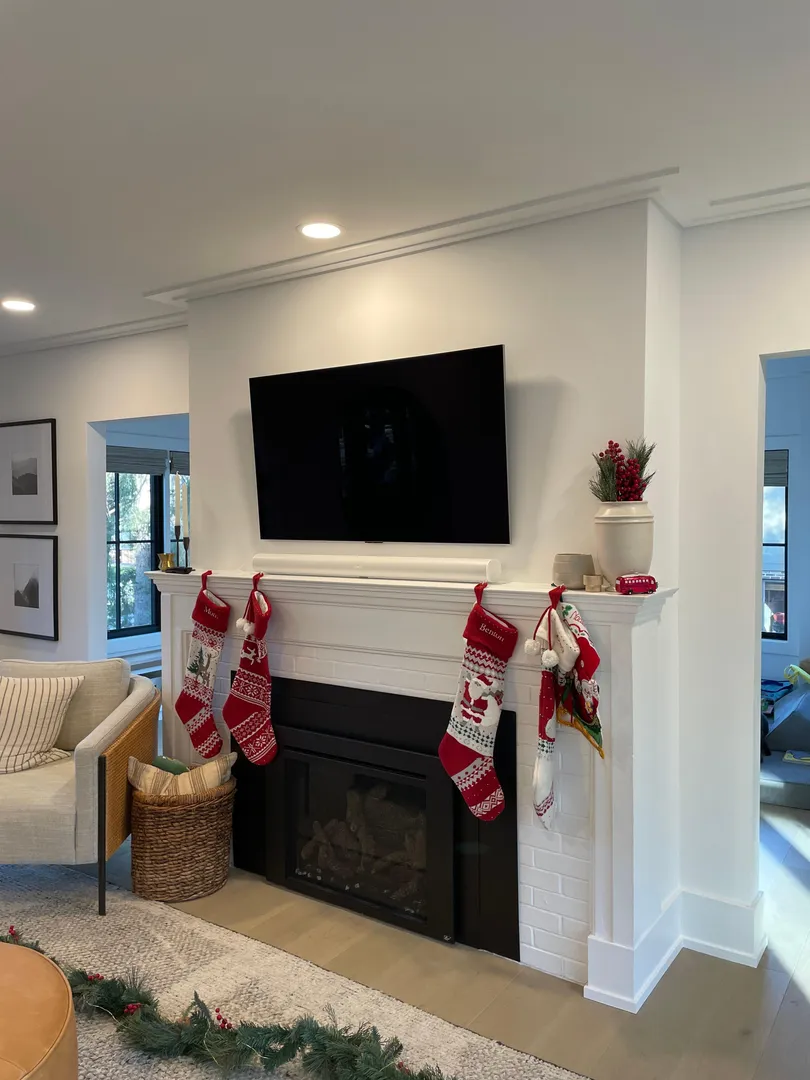 TV mounted above a fireplace with holiday stockings