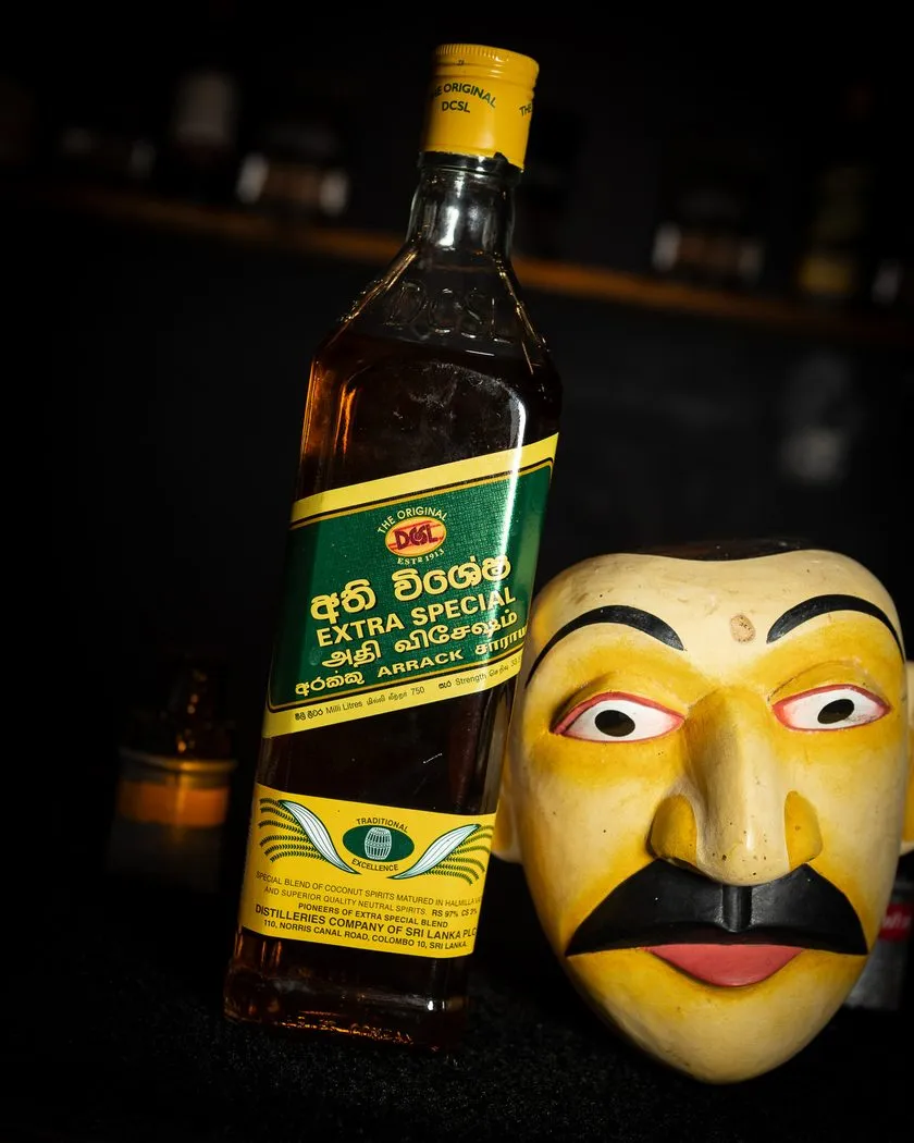 Sri Lankan arrack bottle beside a traditional carved mask