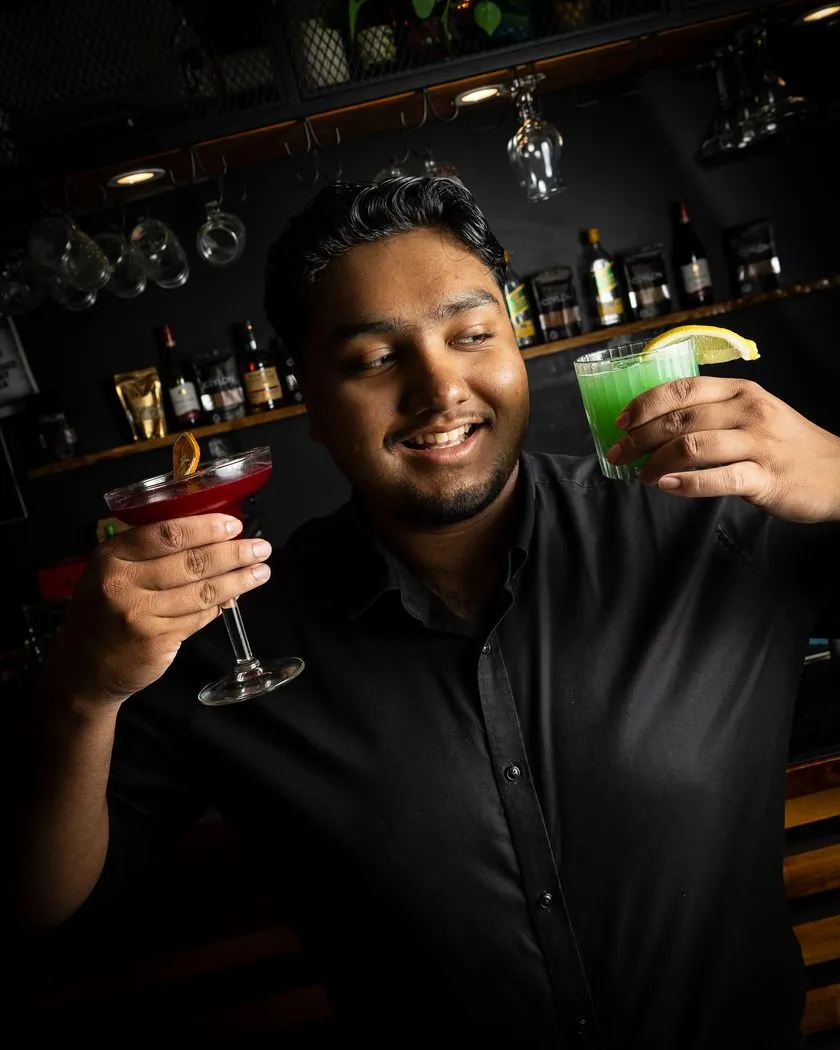 Smiling Walkway to Ceylon bartender holding two cocktails