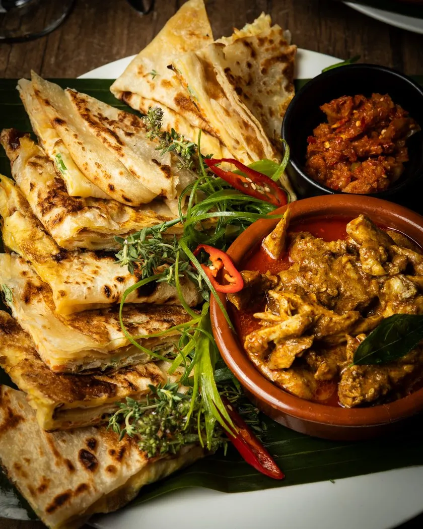 Folded godhamba roti served with curry and sambol on a banana leaf