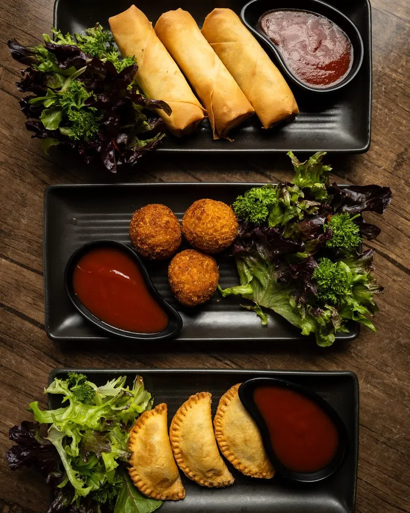 Starter platter of spring rolls, fish cutlets and patties with sauces