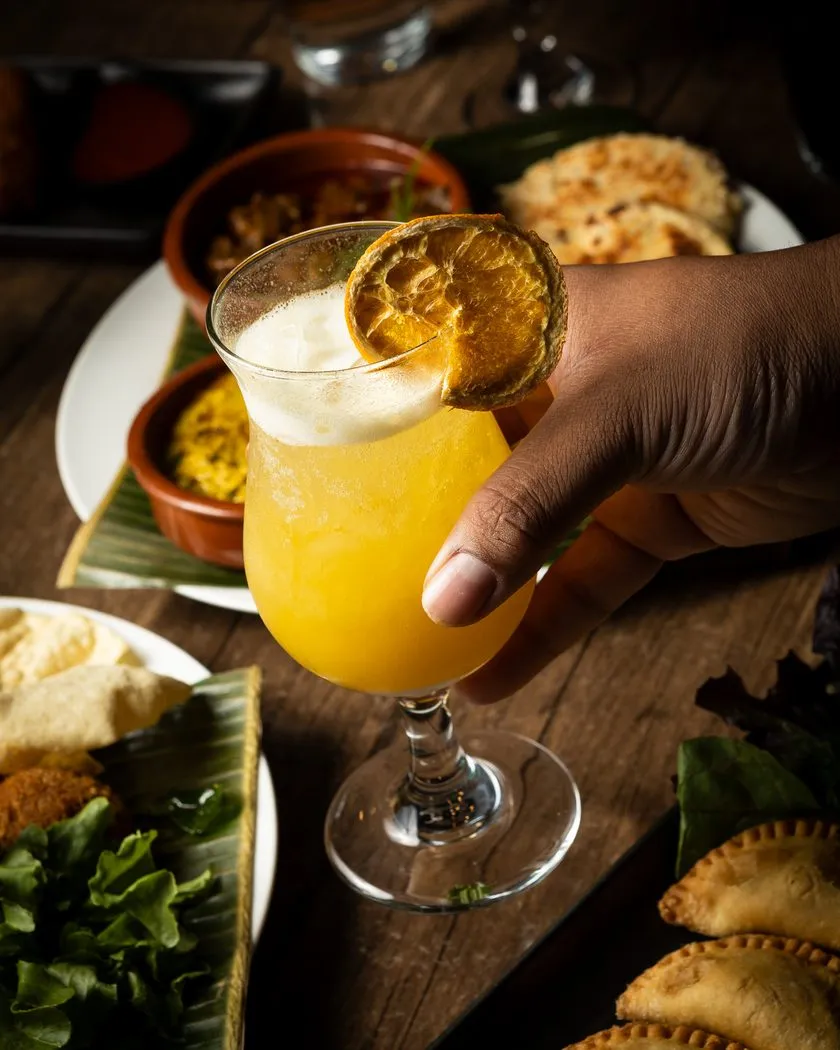 Golden mocktail with an orange garnish held over the table
