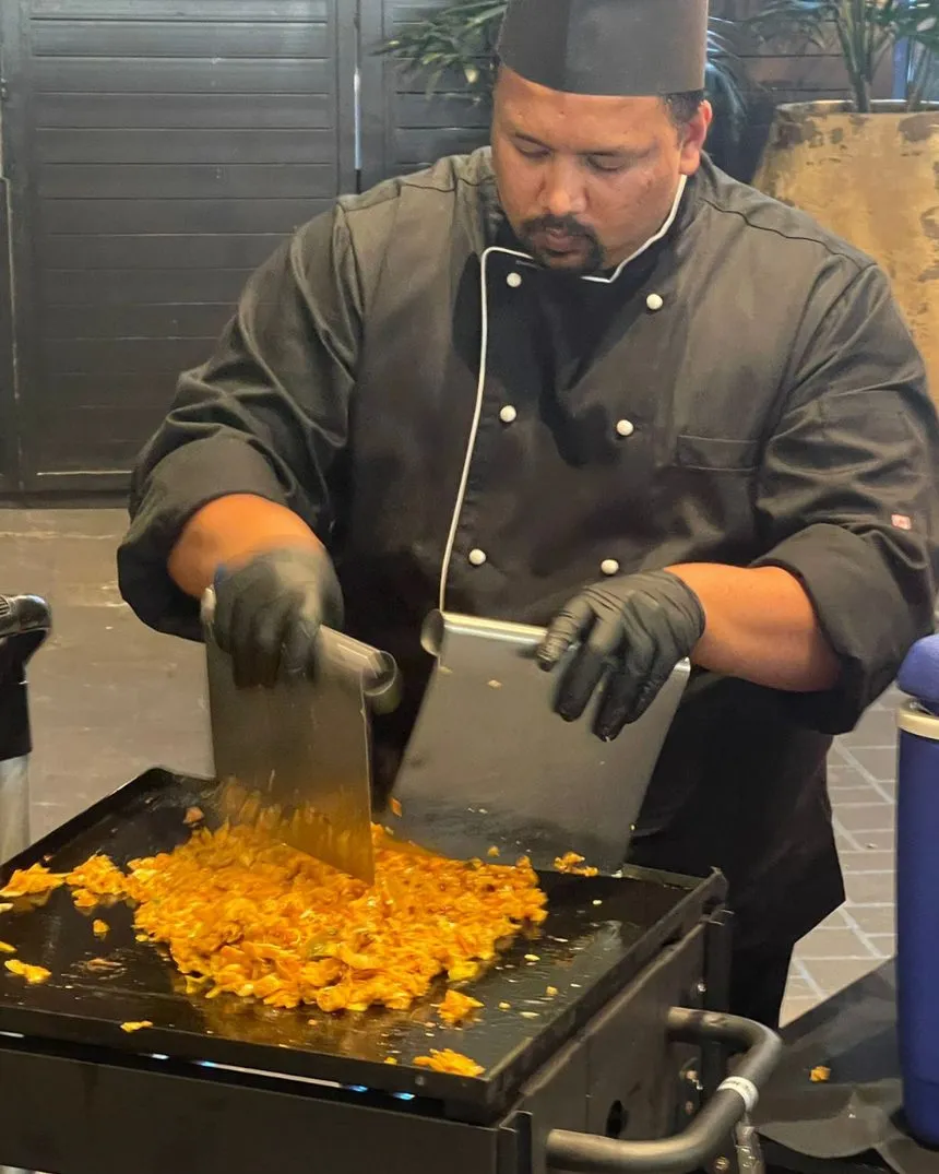 A chef chopping kottu roti on the live kottu station at an event