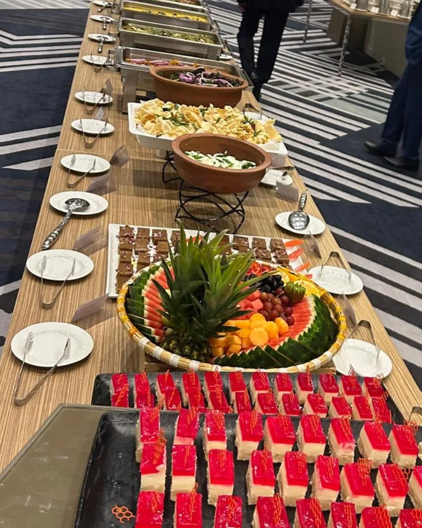 A long catered buffet with clay pots, fruit and desserts