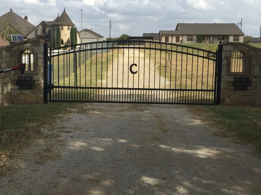 Arched iron driveway gate between stone columns