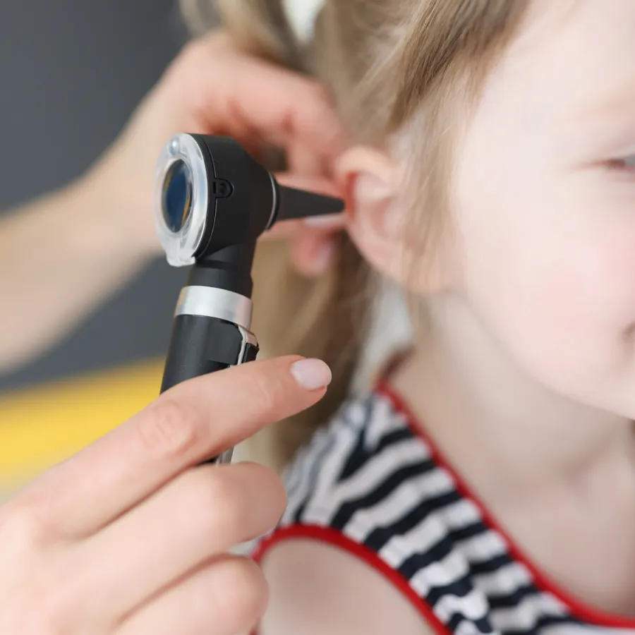 Provider checking a young child's ear with an otoscope