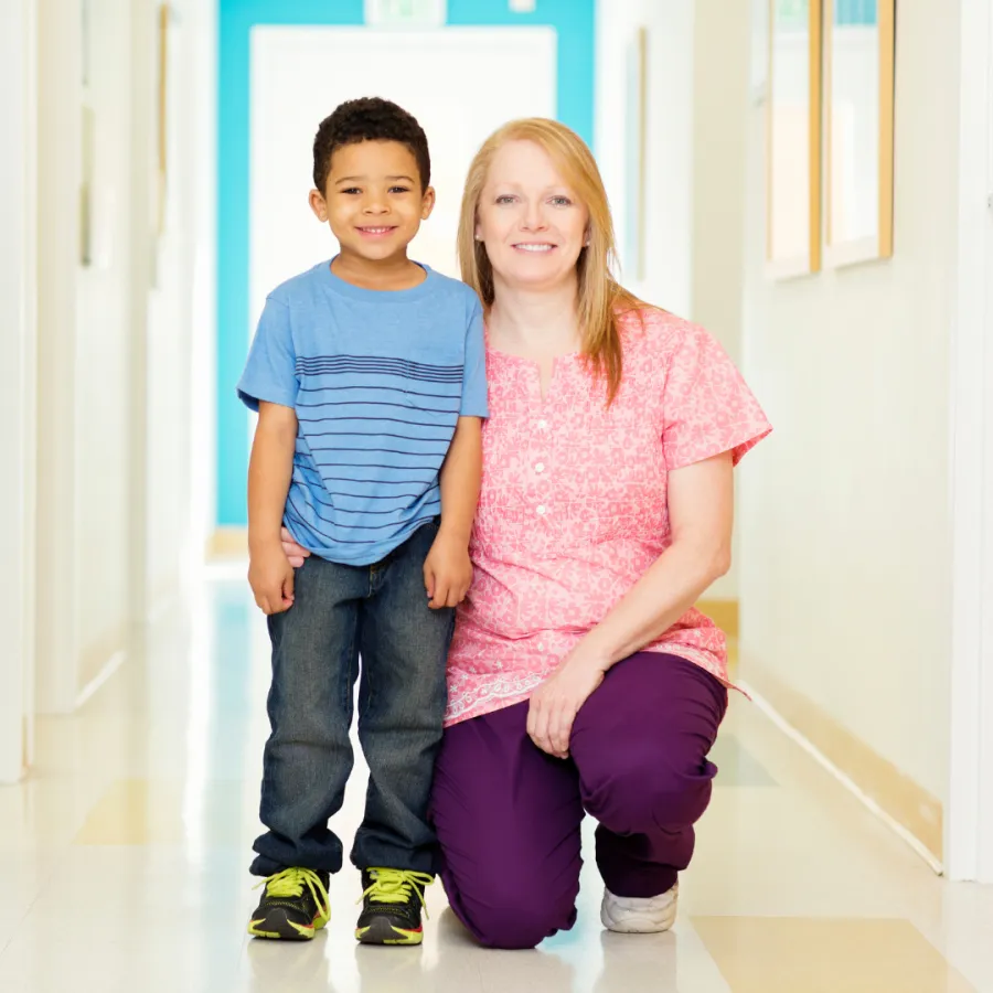Smiling care team member with two children in a bright clinic hallway