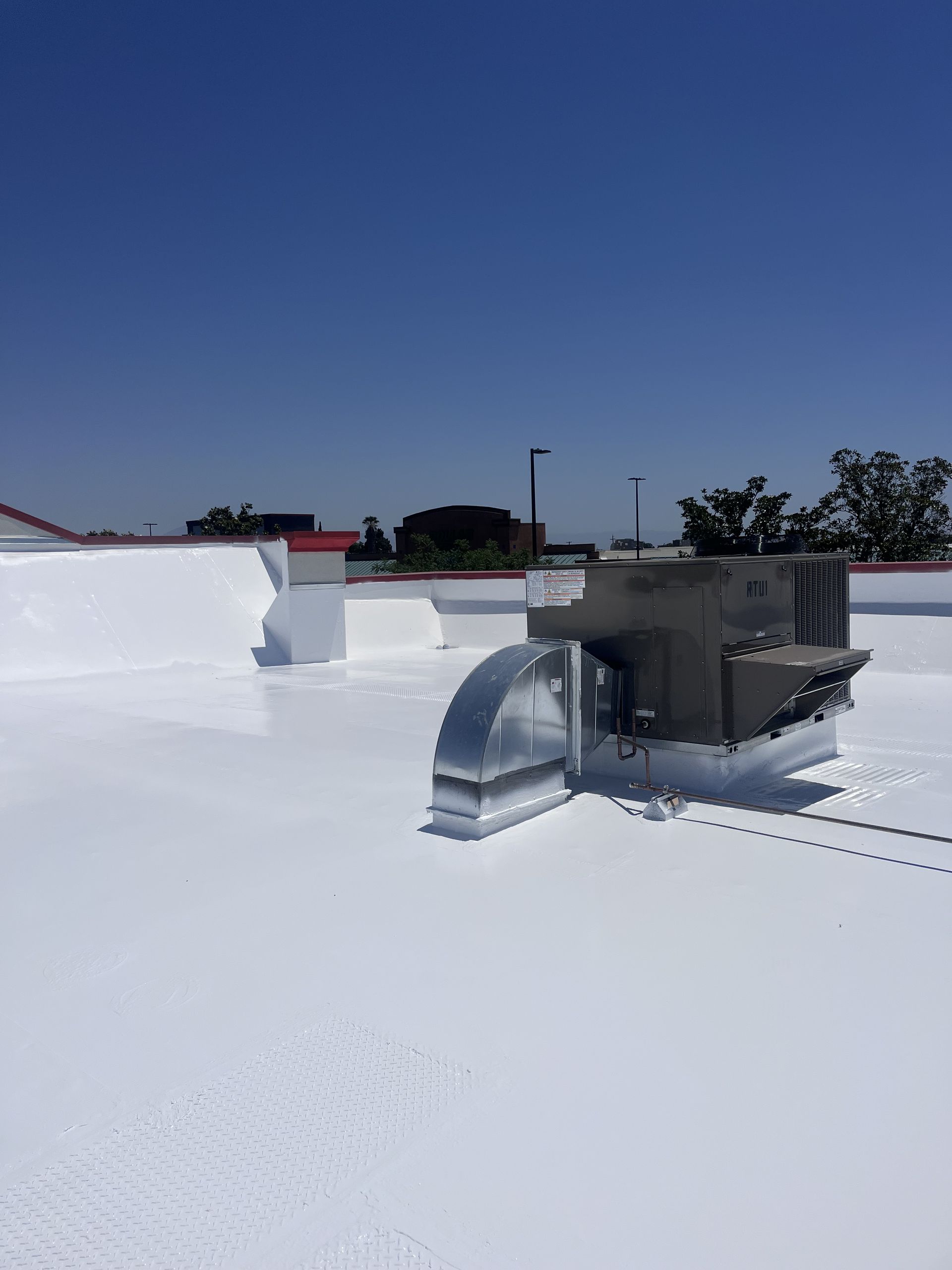 Bright white roof coating on a Bakersfield commercial roof with a rooftop HVAC unit