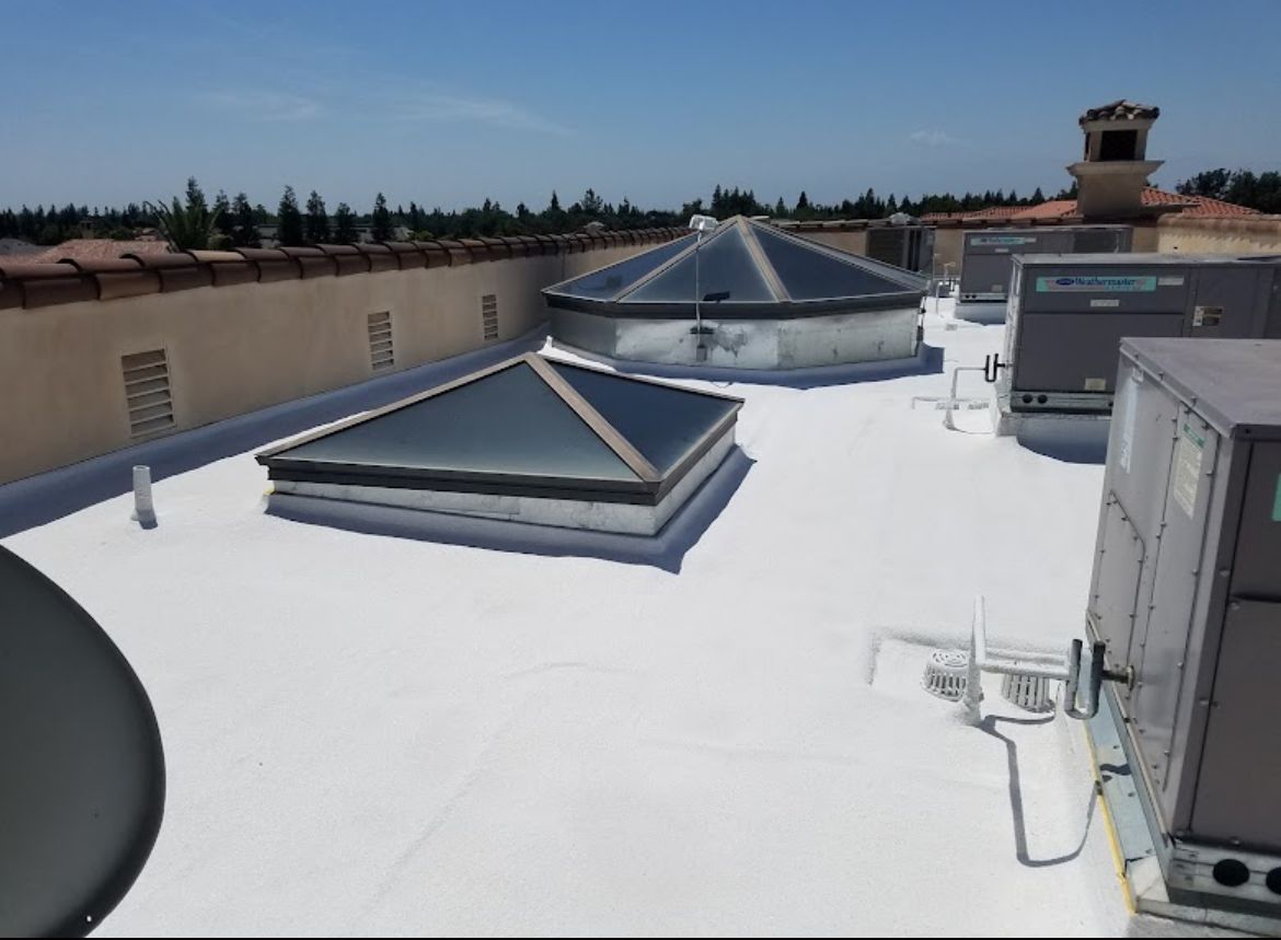 White-coated commercial flat roof with pyramid skylights and rooftop HVAC units