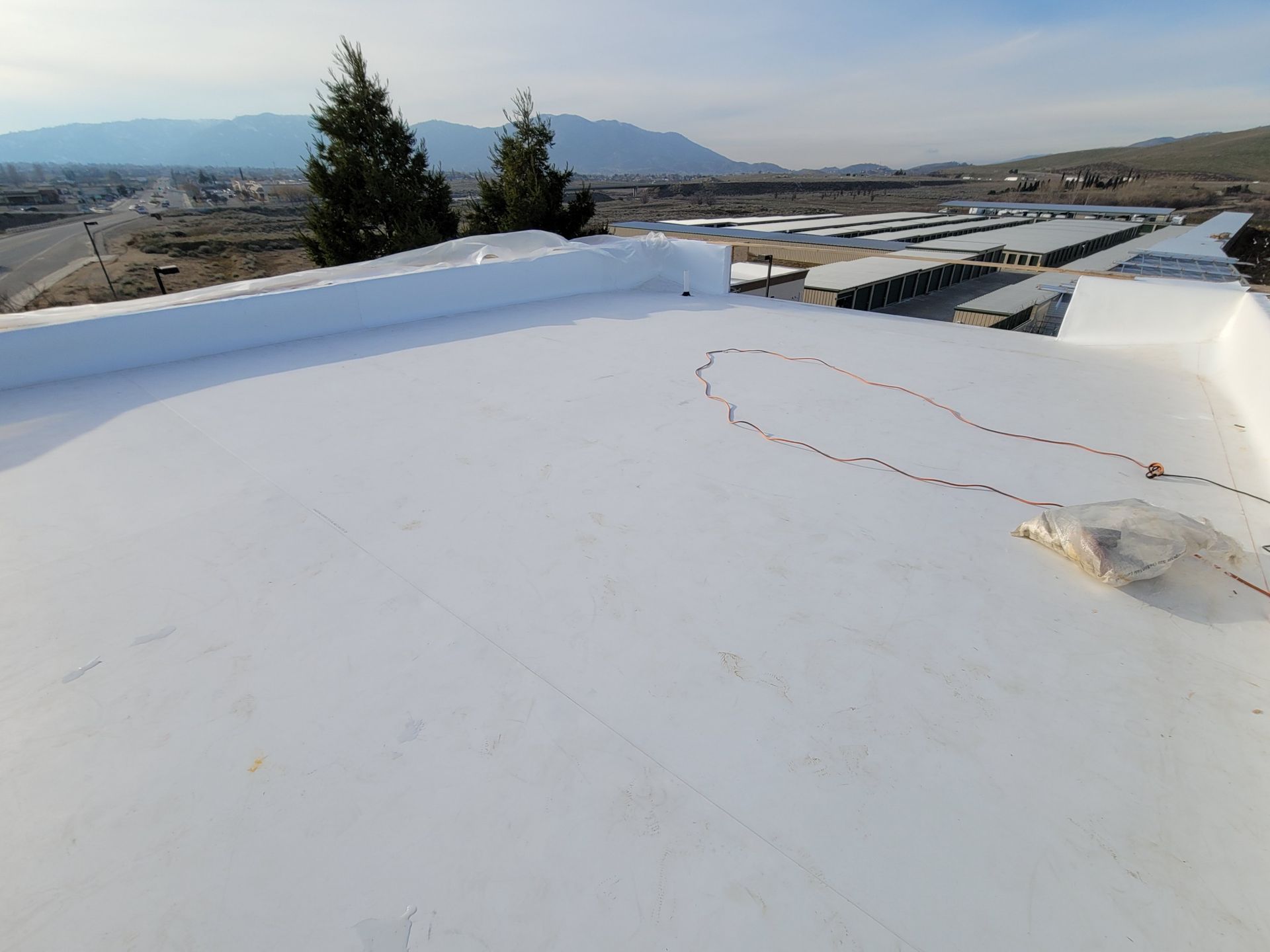 White TPO roof on a commercial building in Kern County with mountains behind