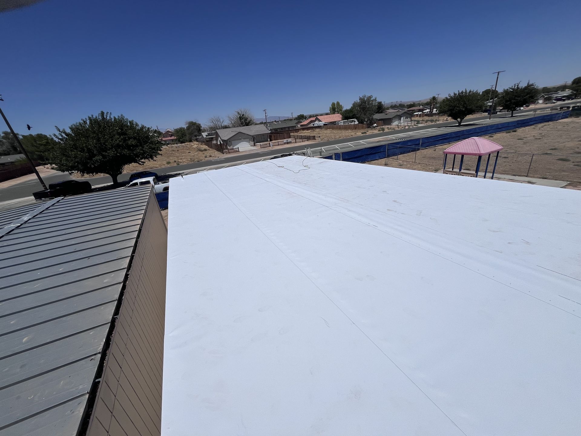 White TPO flat roof next to a standing-seam metal roof in eastern Kern County