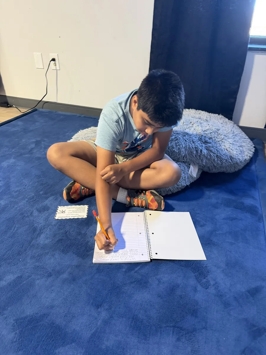 A Spark learner writing in a notebook on the rug