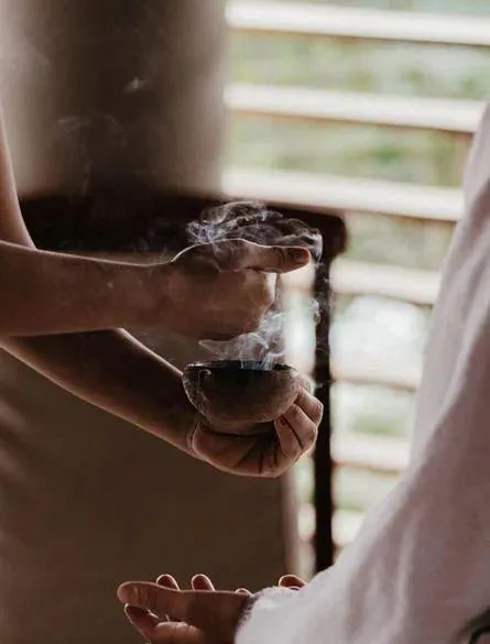 Hands holding a smoking bundle of palo santo