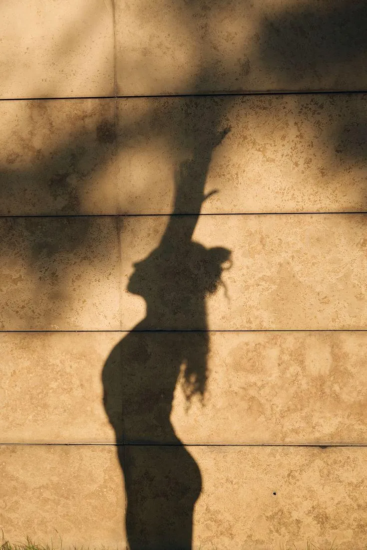 Silhouette on a sunlit stone wall — emotional liberation