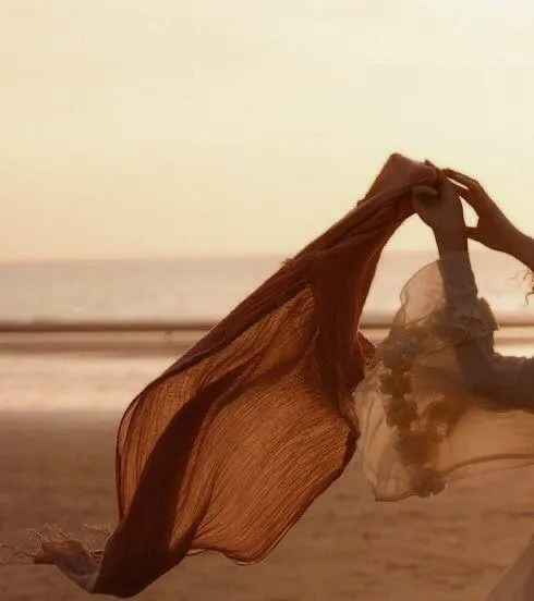 Woman in a flowing rust-colored dress moving in the wind