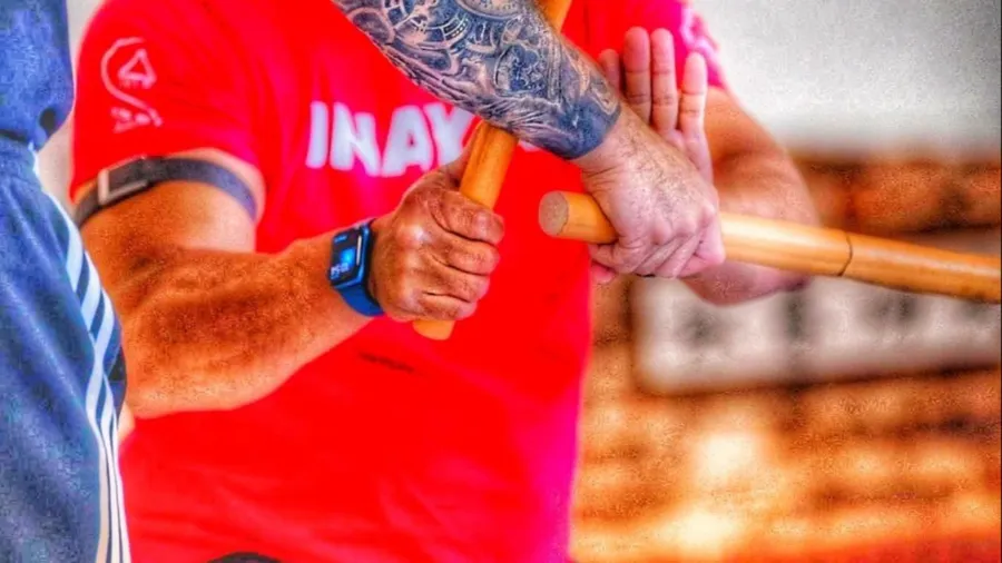 Hands gripping rattan sticks in Inayan Serrada stick training