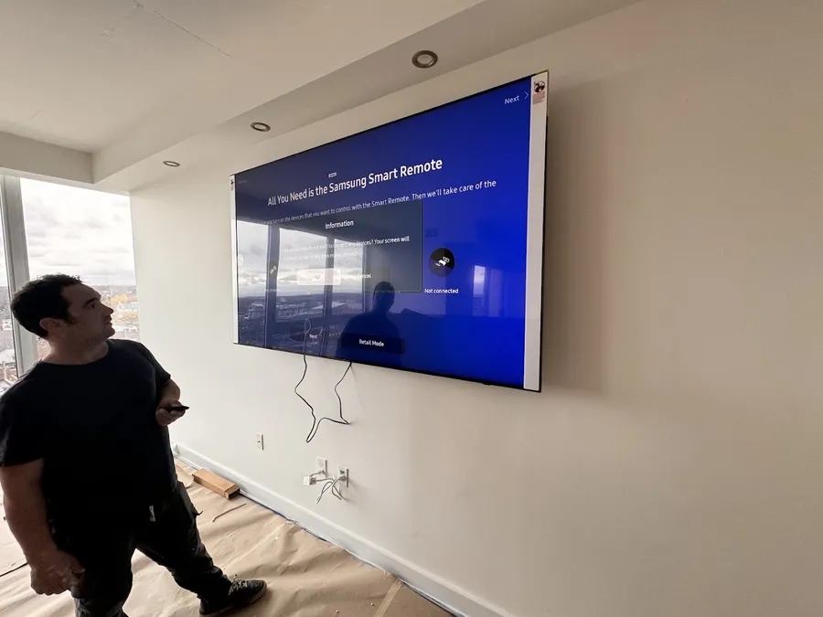 Technician next to a large wall-mounted TV during setup