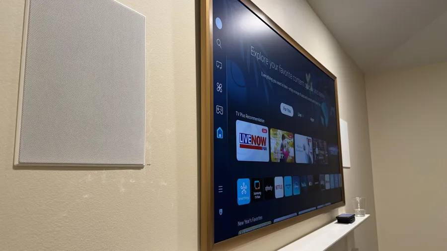 Samsung Frame TV with a wood bezel next to an in-wall speaker