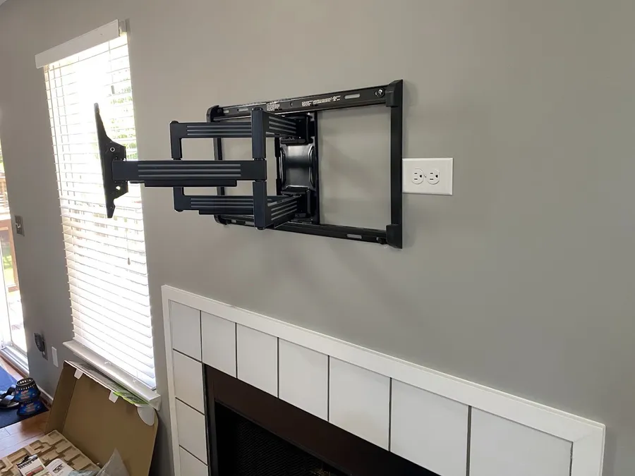 Full-motion TV wall mount installed next to a fireplace