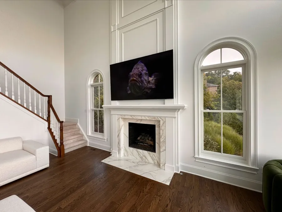 TV showing artwork above a white marble fireplace