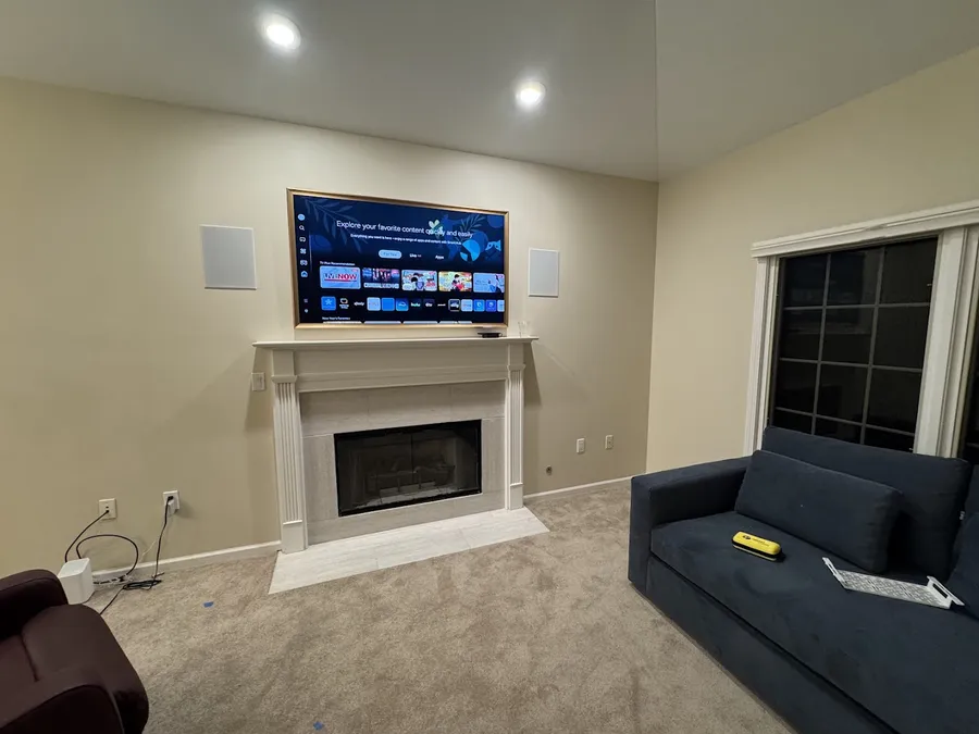 TV above a fireplace with in-wall speakers on both sides
