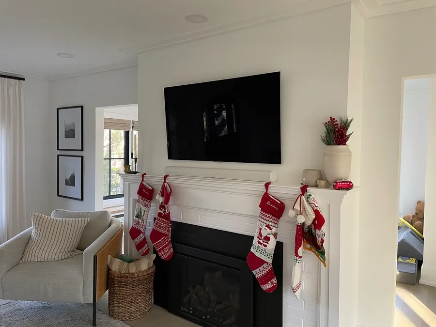 TV above a white mantel decorated with stockings