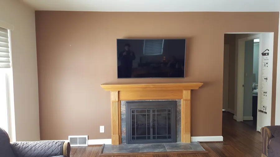 TV mounted above a wood fireplace mantel