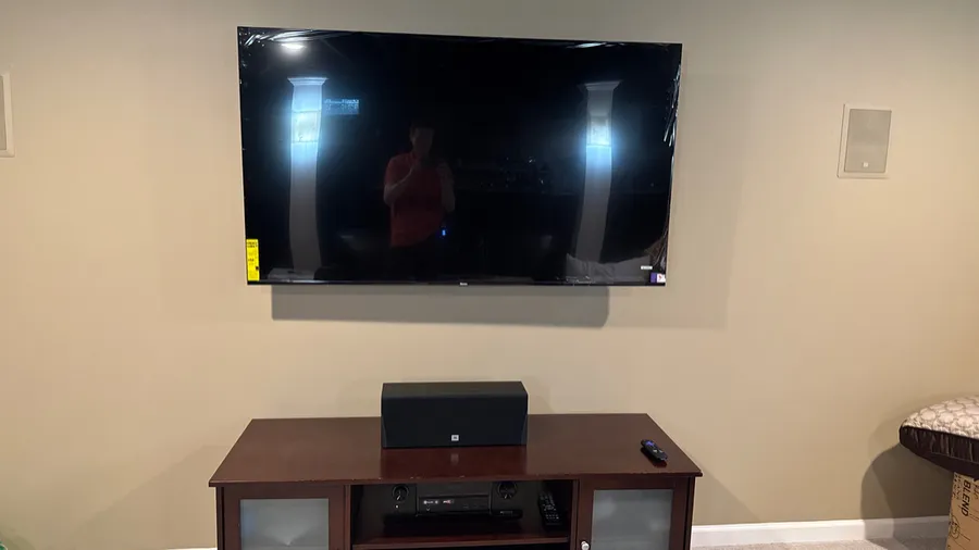 Wall-mounted TV with a center channel speaker and an in-wall speaker