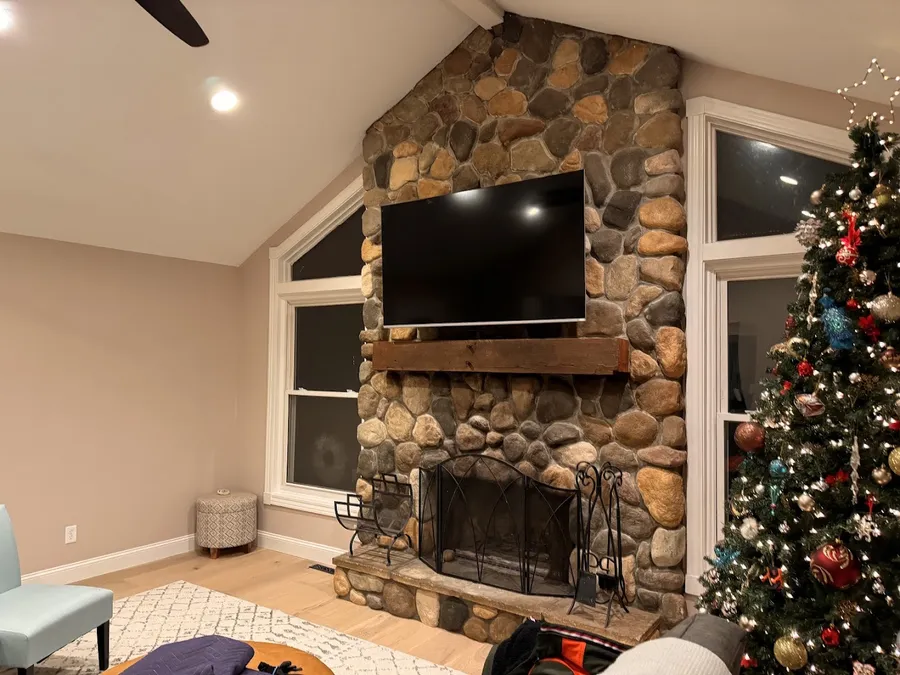 TV mounted on a river rock fireplace in a vaulted living room