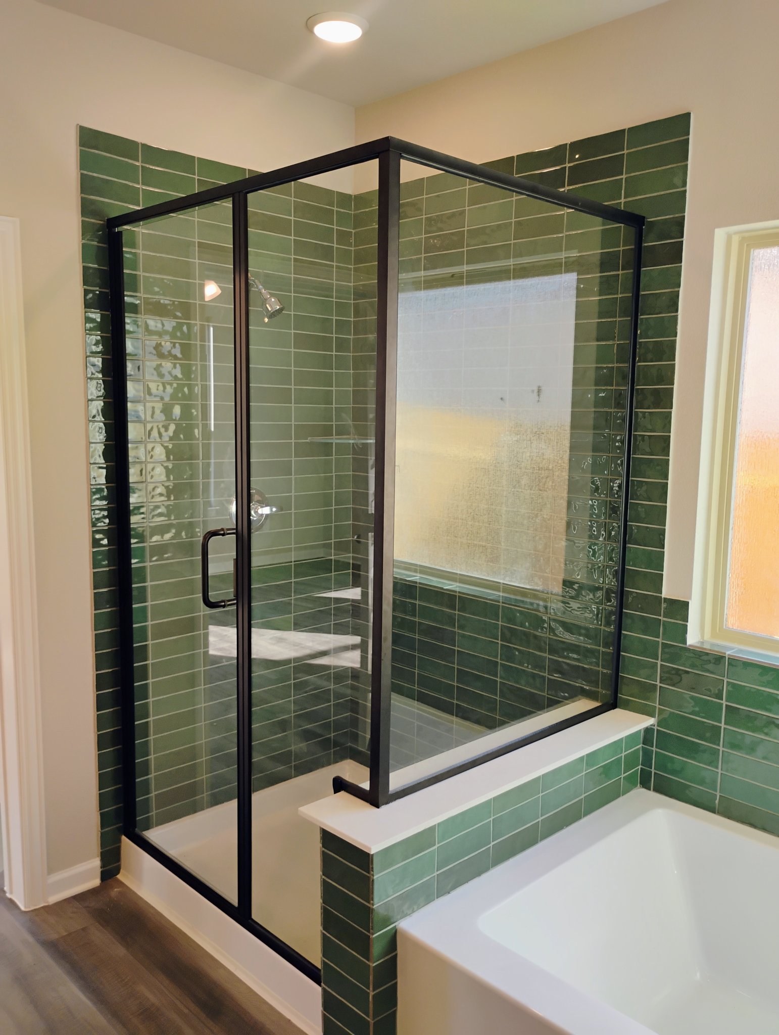 Black-framed shower glass on green tile