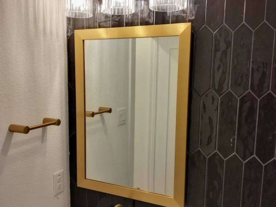 Gold-framed mirror on dark picket tile