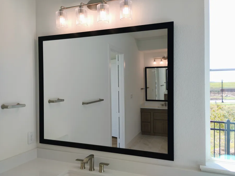 Large black-framed vanity mirror with a window view