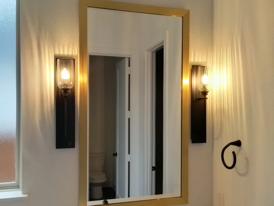 Brass-framed mirror with black sconces