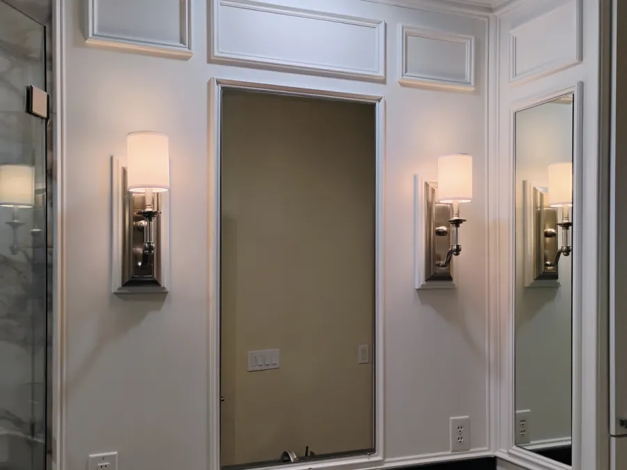 Built-in framed mirror between two sconces