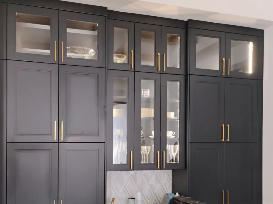 Dark kitchen cabinets with glass-front uppers and brass pulls