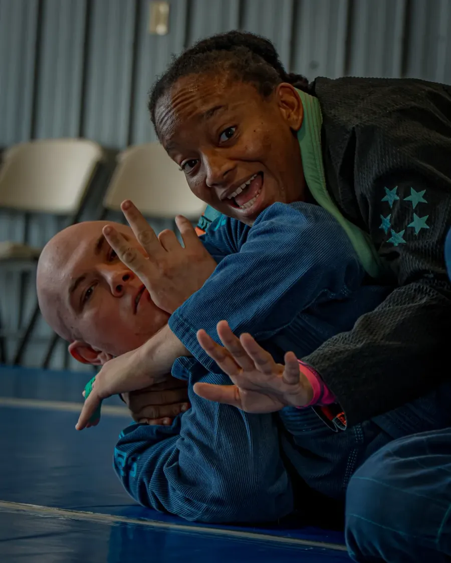 A smiling student training jiu-jitsu with a partner at Delta Grappling Academy