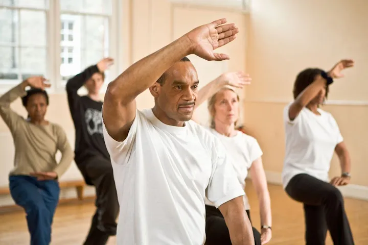 Adults practicing slow Tai Chi movements together