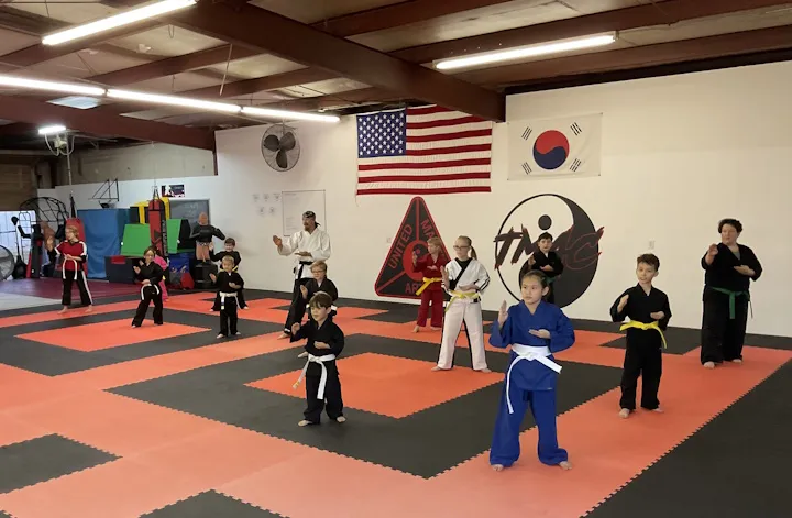 Kids lined up practicing Taekwondo on the dojo mats