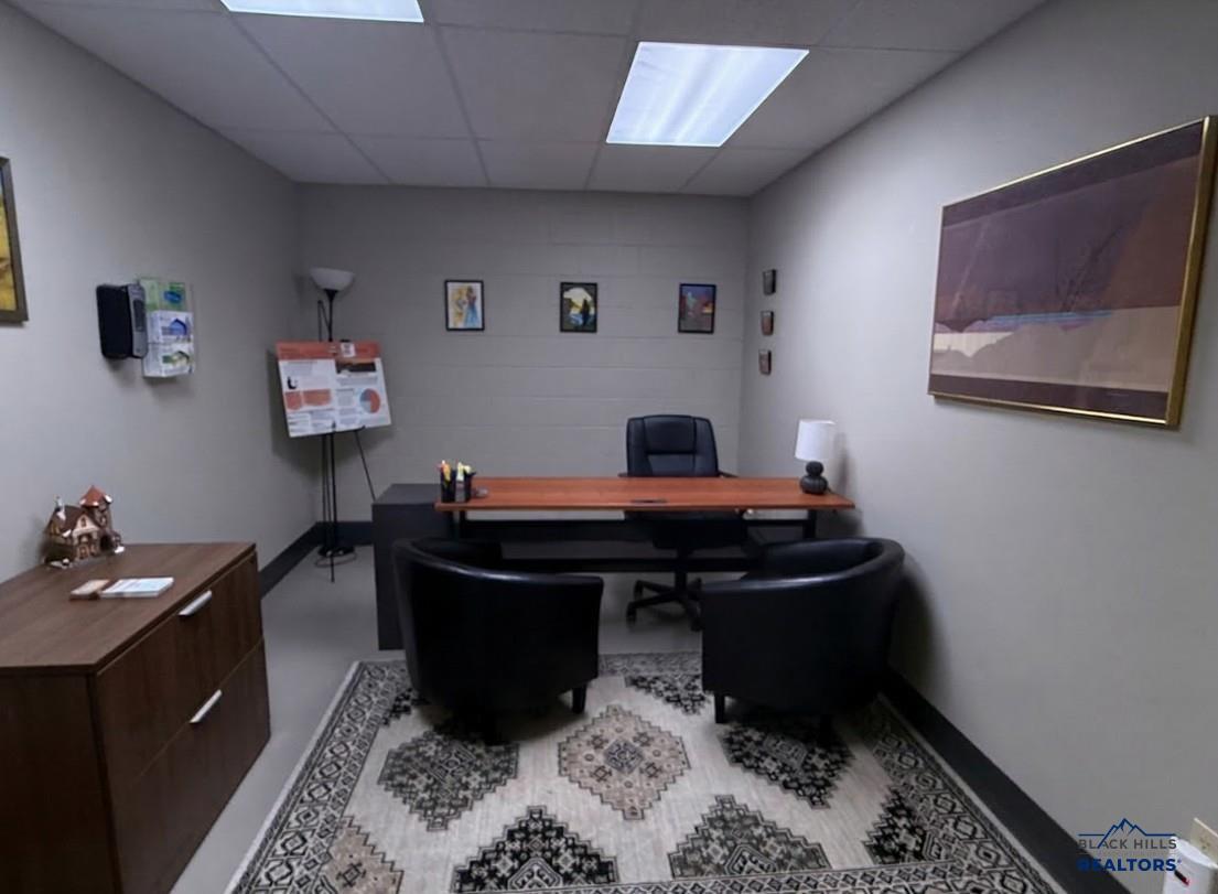 Private office with a desk, two guest chairs and a patterned rug