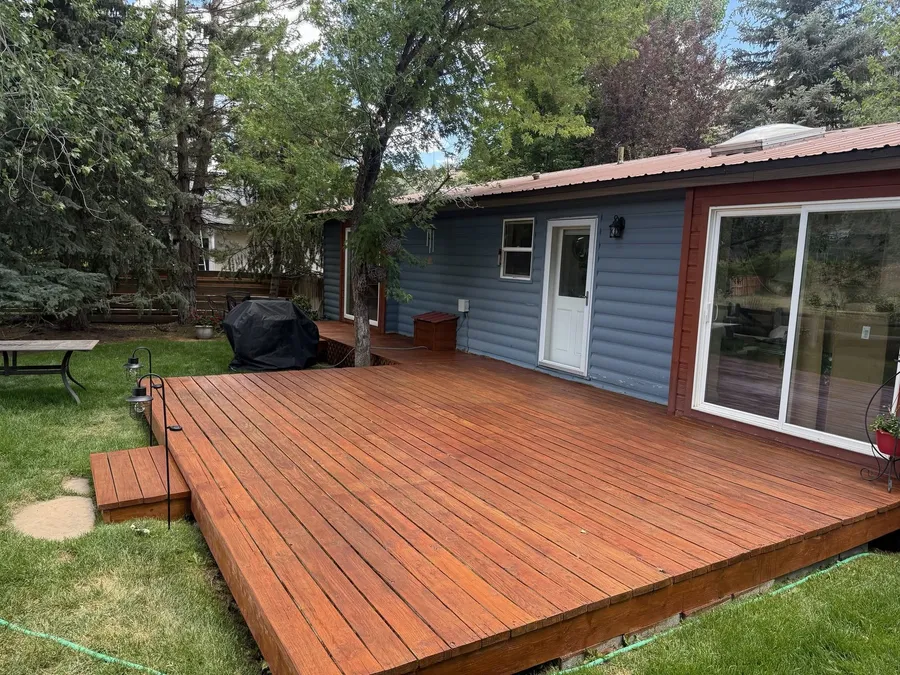 Large backyard deck freshly stained a warm cedar color with a step down to the lawn