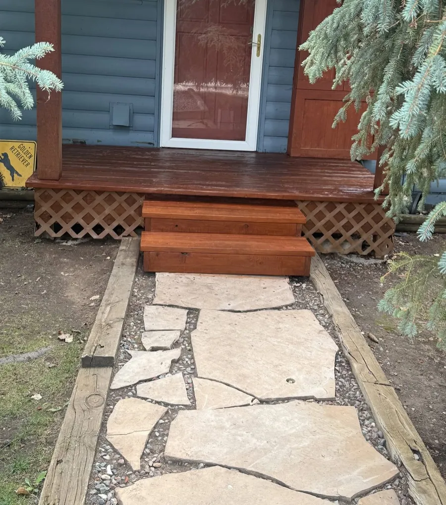 New stained wooden steps leading from a front porch down to a flagstone path