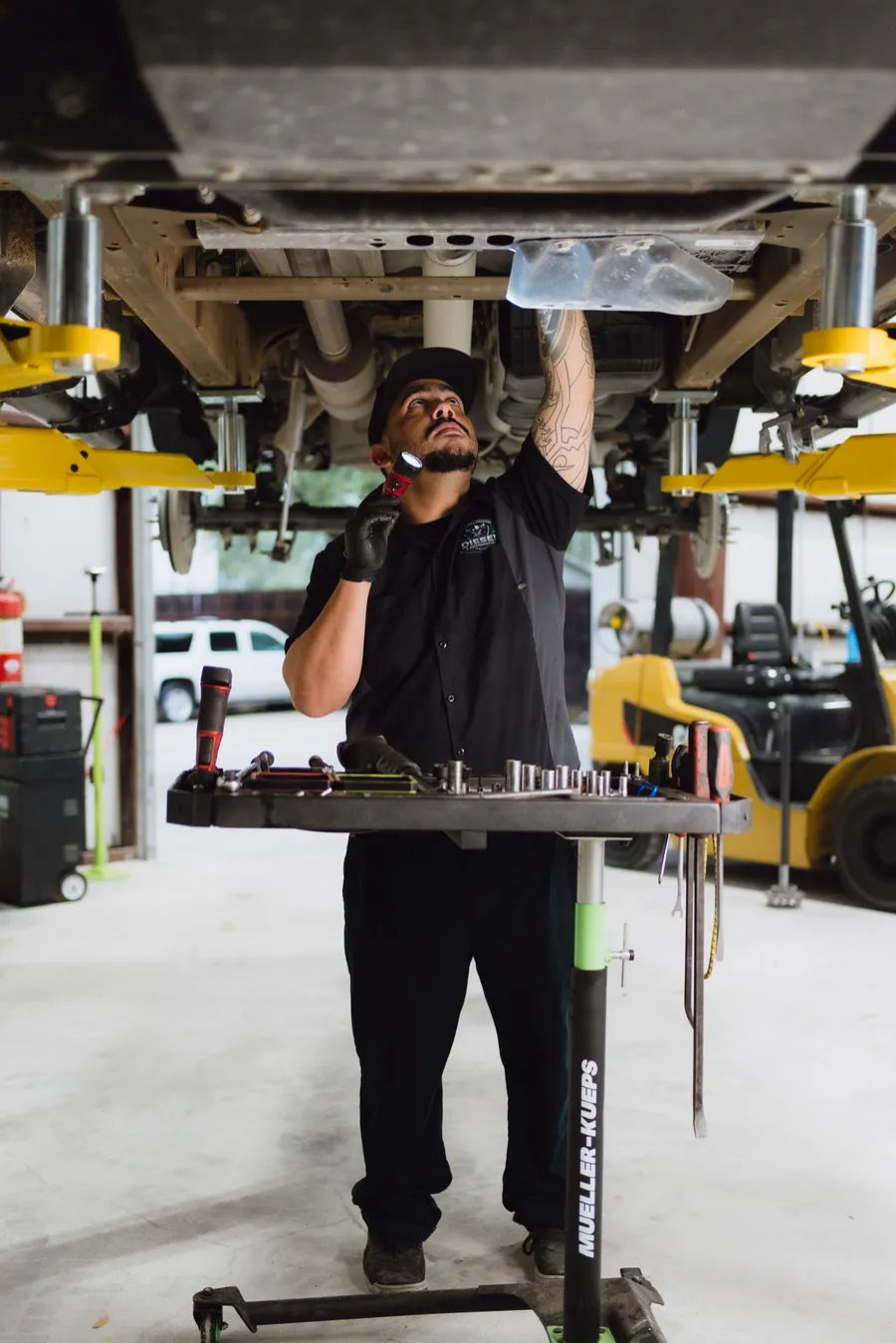 Technician working under a vehicle with a tool cart