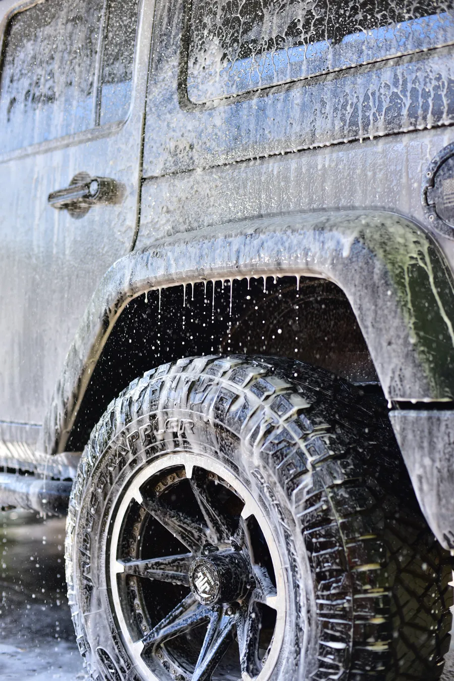 Jeep wheel and fender covered in wash foam during a hand wash