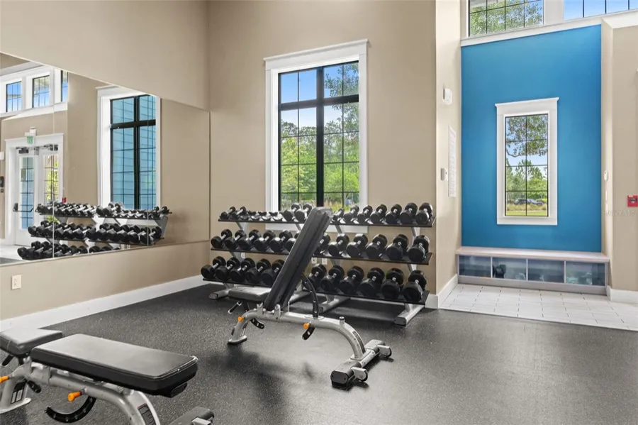 Fitness center with free weights and large windows at the Bexley clubhouse